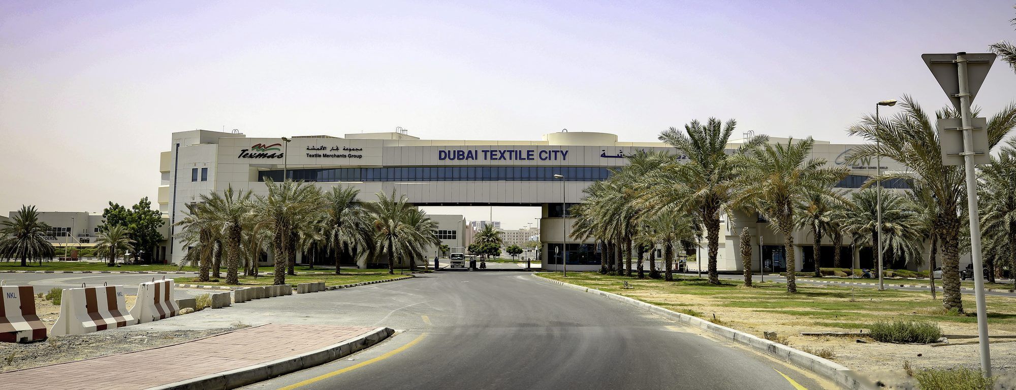 The avenue into Dubai Textile City, the TEXMAS mark and Textile Merchants Group name on the gateway building
